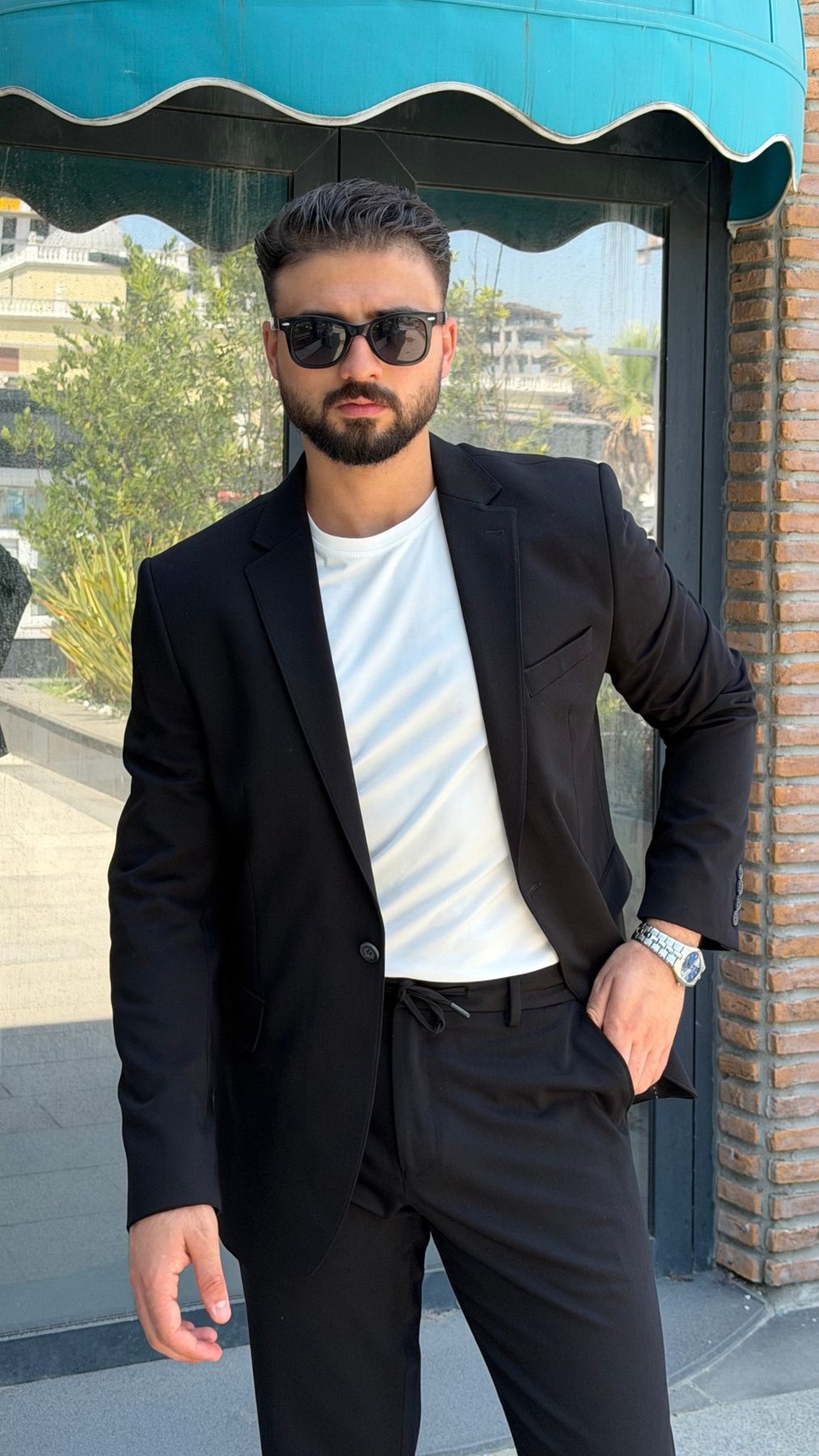 Men's black two-piece suit styled with a white T-shirt and sneakers