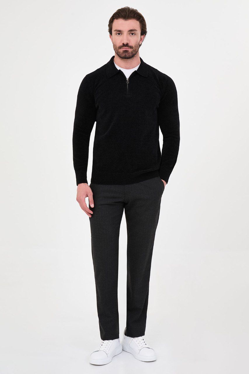 Man wearing a black textured quarter-zip polo sweater with black trousers