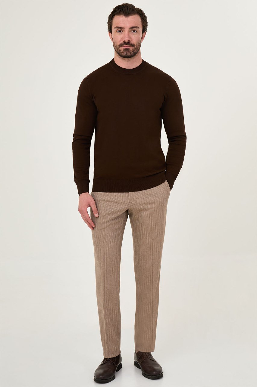 Man wearing a brown crew neck sweater with beige trousers