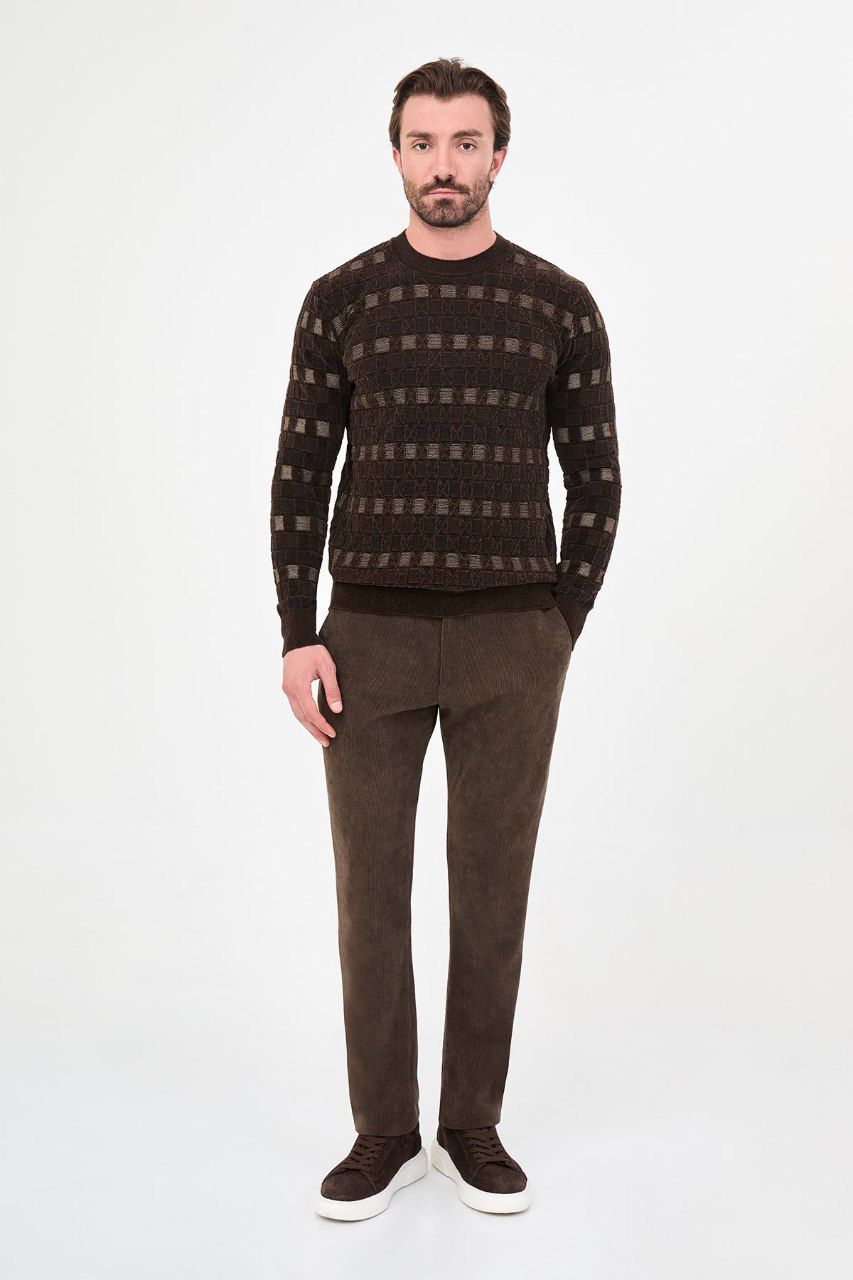 Man wearing a brown geometric crew neck sweater with brown trousers