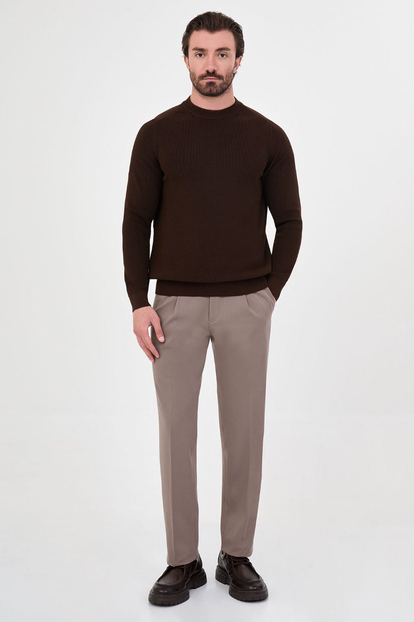 Man wearing a brown ribbed raglan crew neck sweater with grey trousers