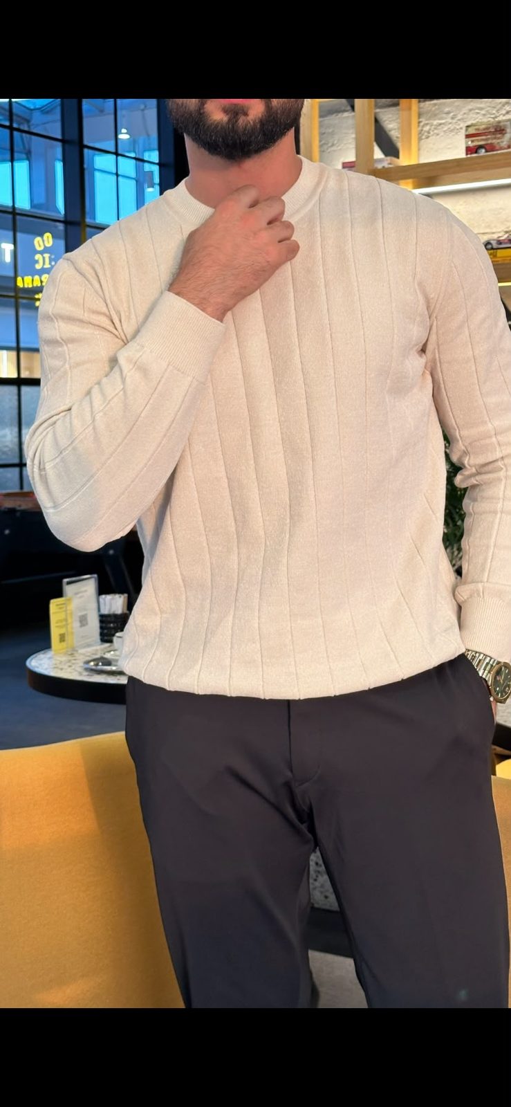 Ecru sweater showing vertical knit detailing and ribbed cuffs
