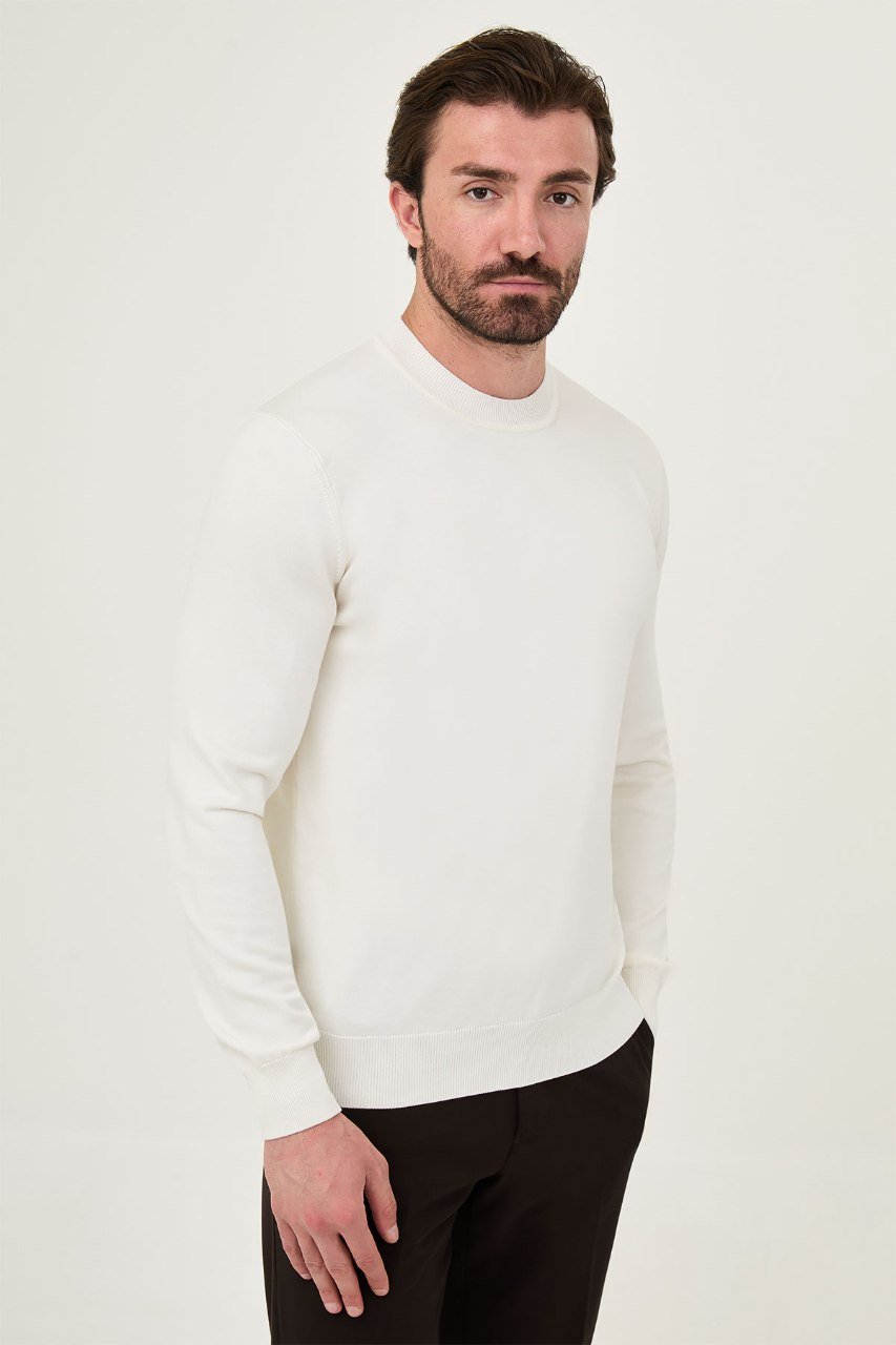Angled view of a man wearing an ecru crew neck sweater