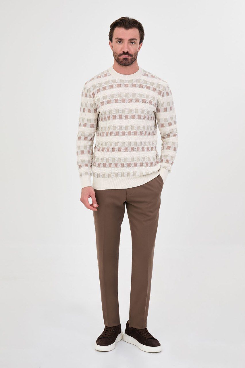 Man wearing a ecru geometric crew neck sweater with brown trousers