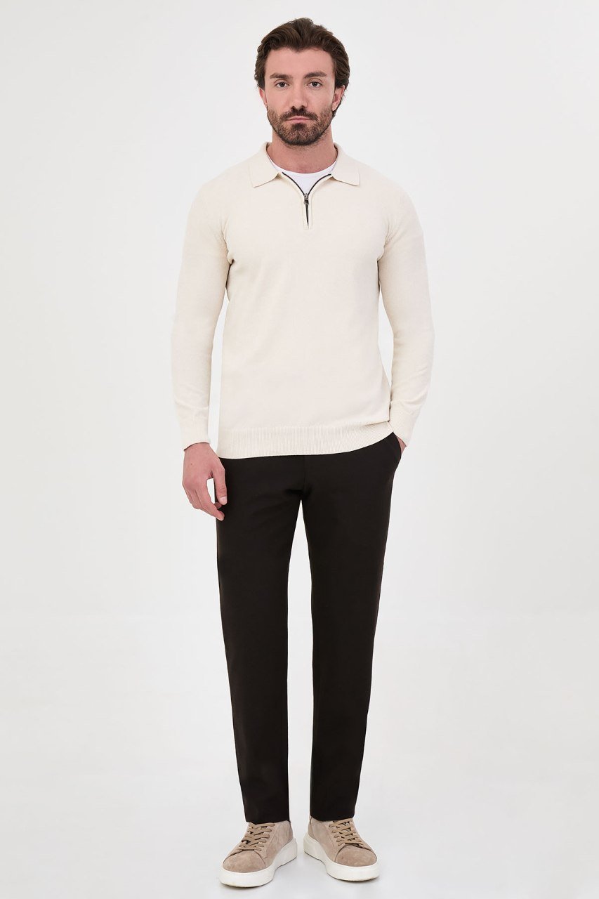 Man wearing a ecru textured quarter-zip polo sweater with black trousers