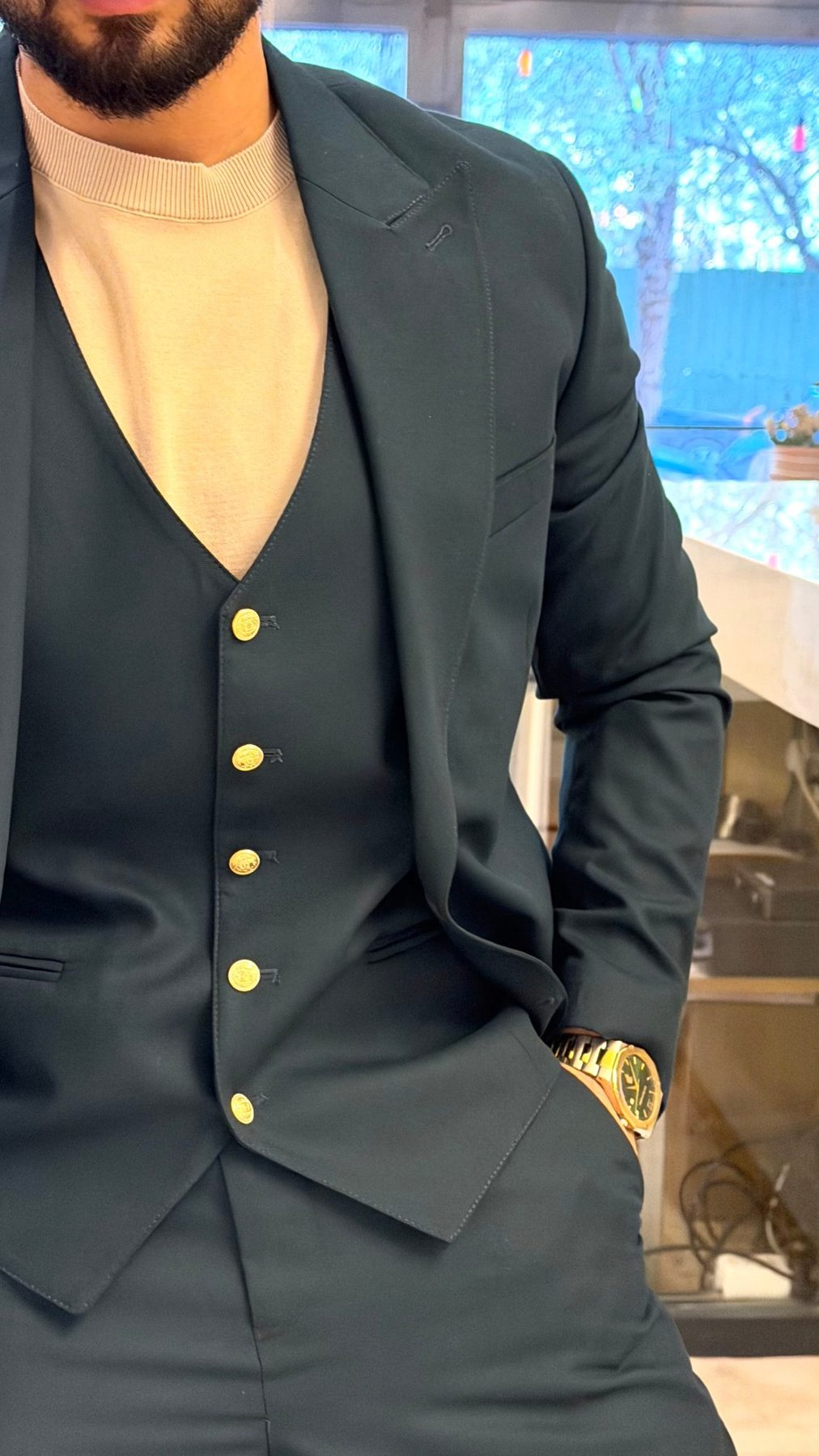 Close-up of emerald green three-piece suit waistcoat and gold-tone button details