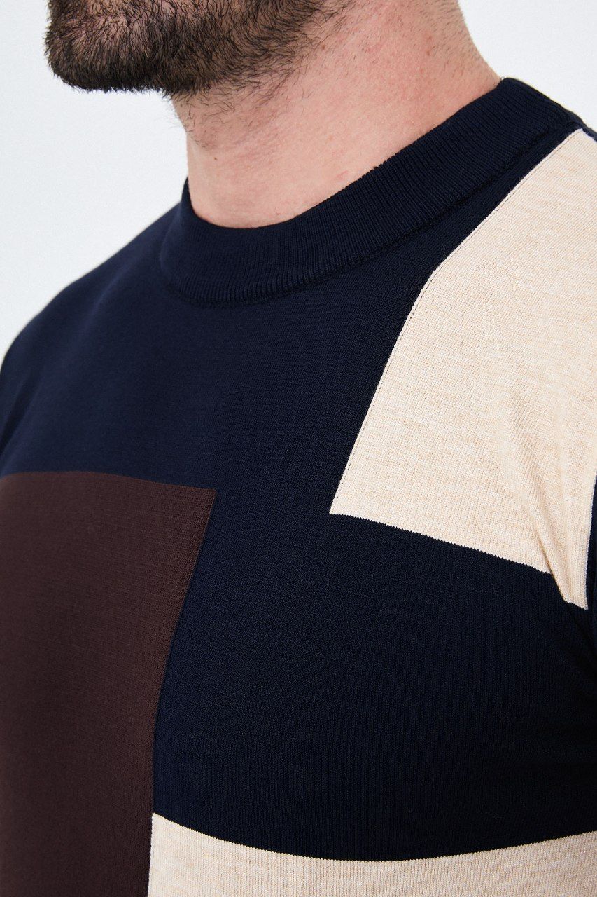 Close-up of the navy blue asymmetric colour-block sweater's crew neckline and contrasting knit panels