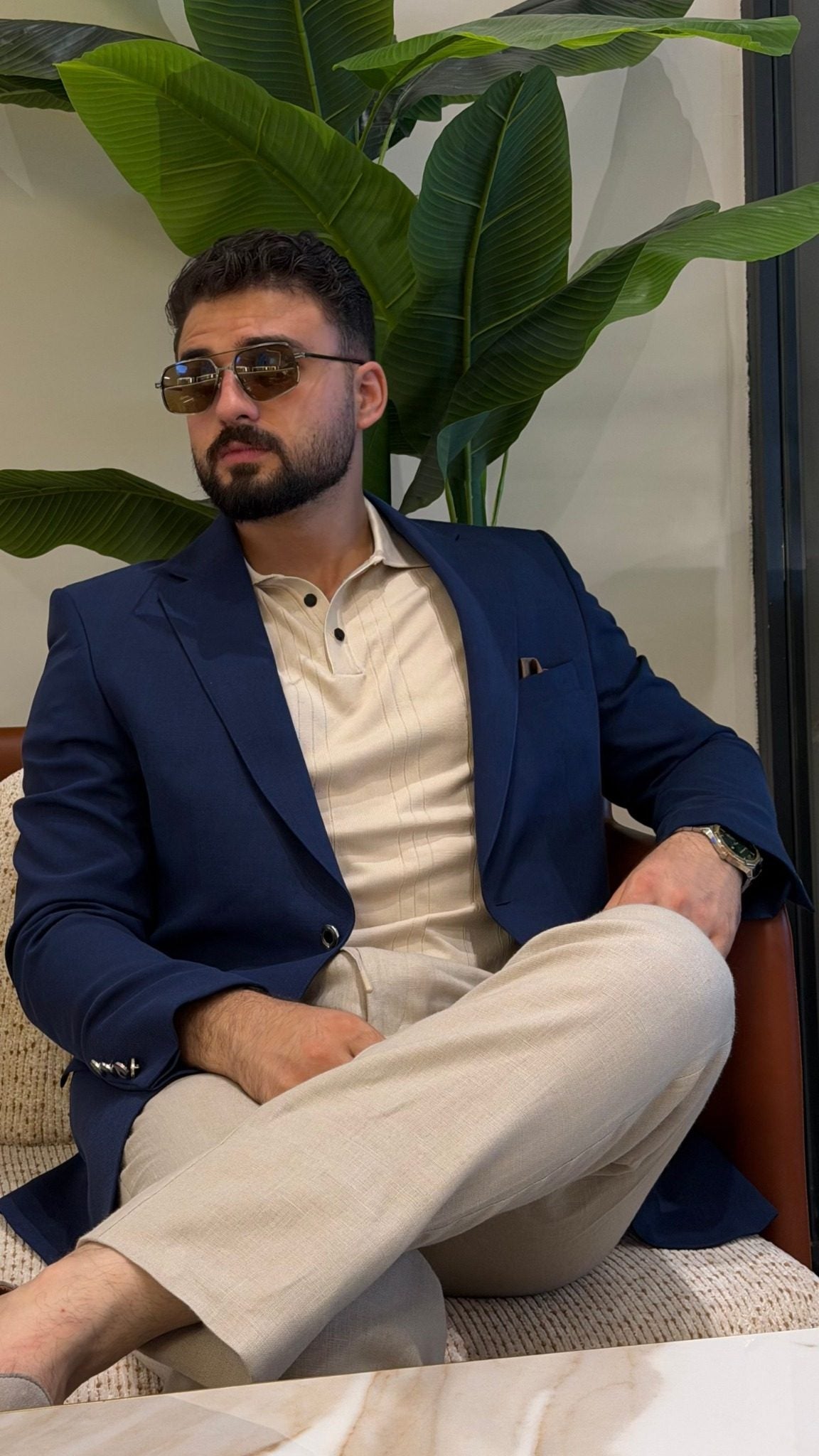 Men's navy blue notch-lapel blazer styled for a smart casual outfit, seated view