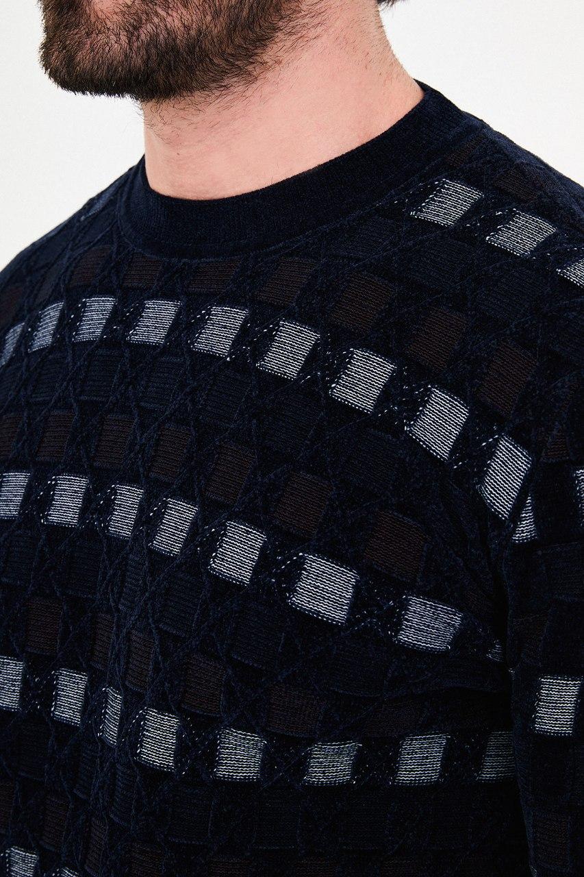 Close-up of square accents and diamond outlines in the navy blue sweater's knit
