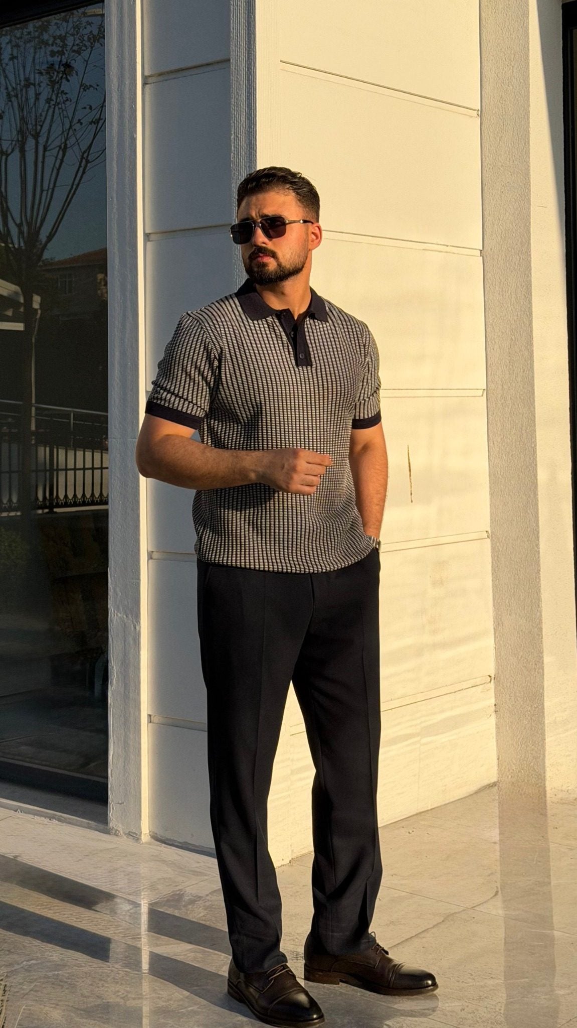 Men's navy blue textured knit polo shirt styled with black trousers, full-length view