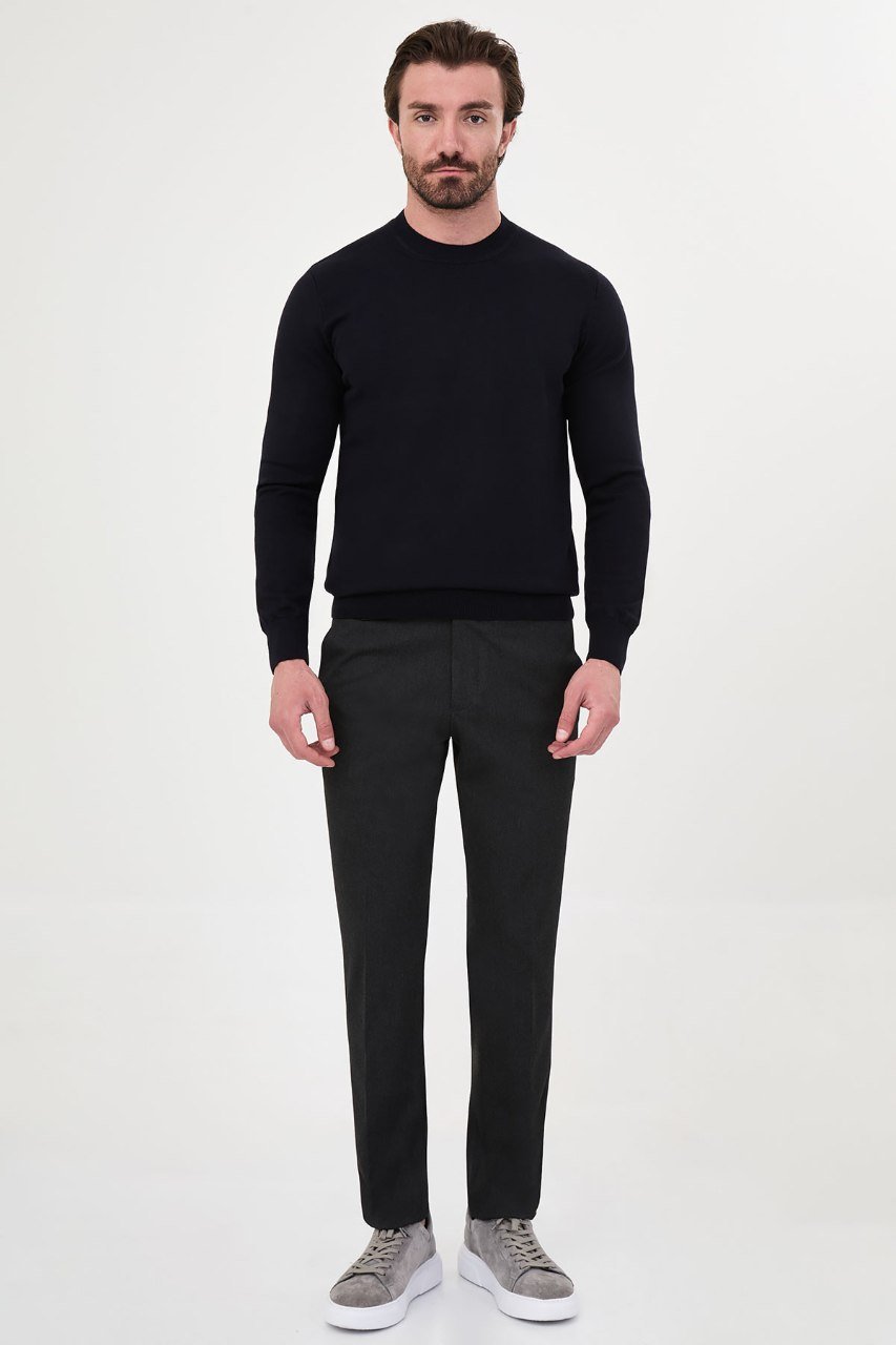 Man wearing a navy crew neck sweater with grey trousers