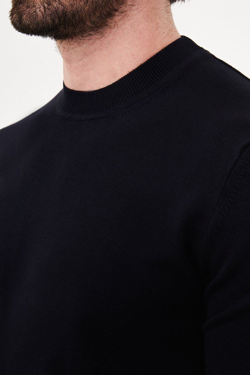 Close-up of the navy sweater's crew neckline and fine knit