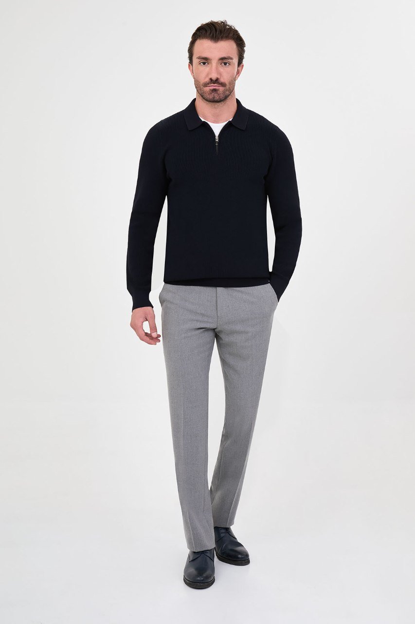 Man wearing a navy ribbed quarter-zip polo sweater with grey trousers