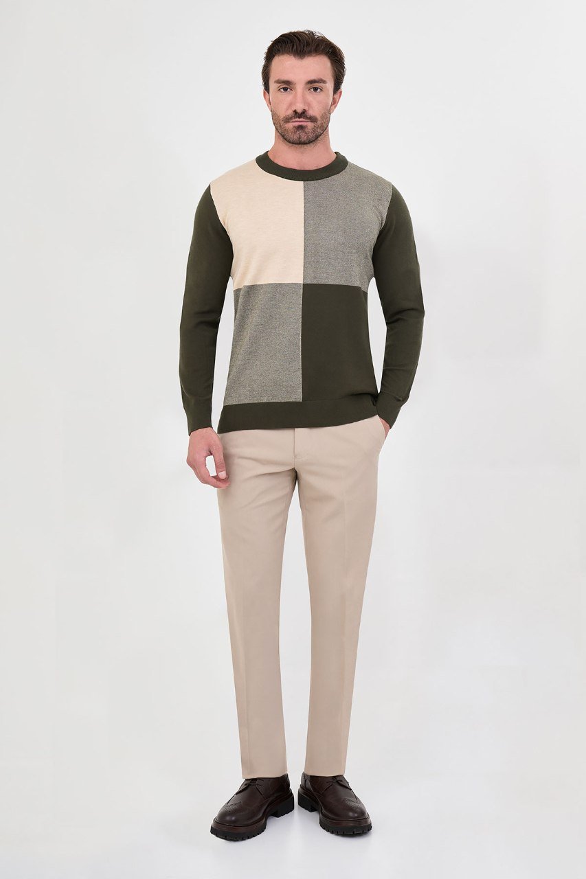 Man wearing a olive green colour-block sweater with beige trousers