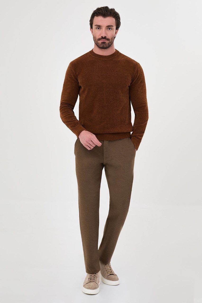 Man wearing a rust textured crew-neck sweater with brown trousers