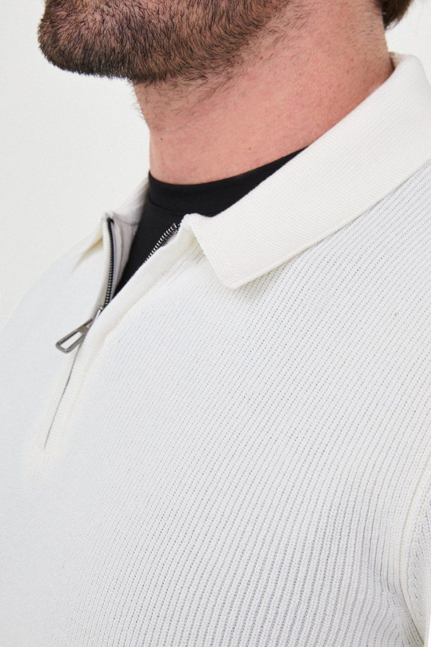 Close-up of the white sweater's ribbed knit, polo collar and metal quarter-zip fastening