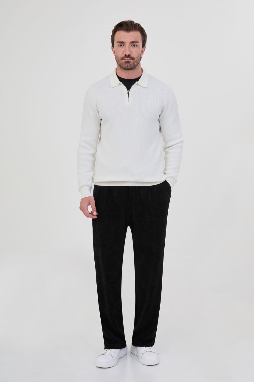 Man wearing a white ribbed quarter-zip polo sweater with black trousers