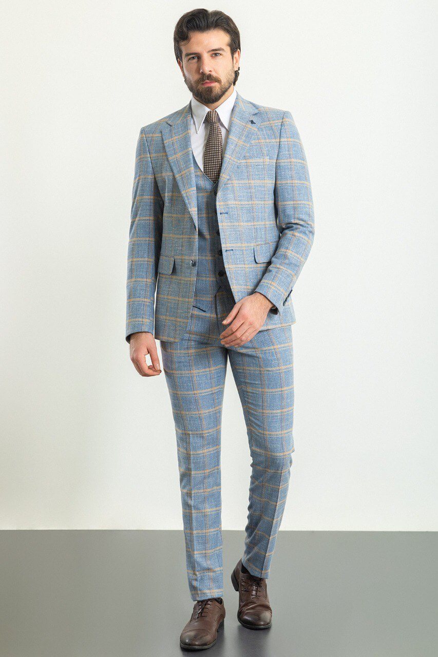 Man in a plaid blue 3-piece suit with a brown tie and brown shoes.