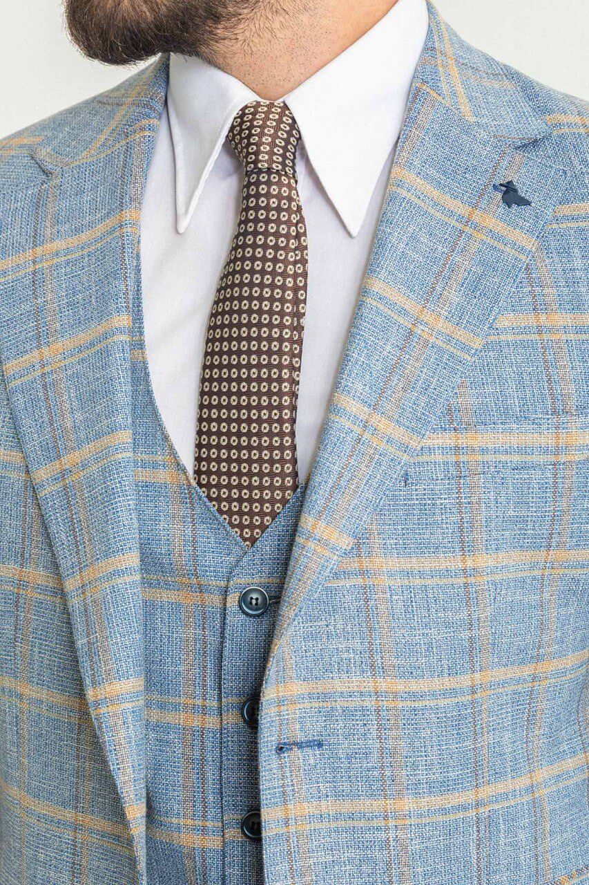 Man in a plaid blue 3-piece suit with a brown tie and brown shoes.