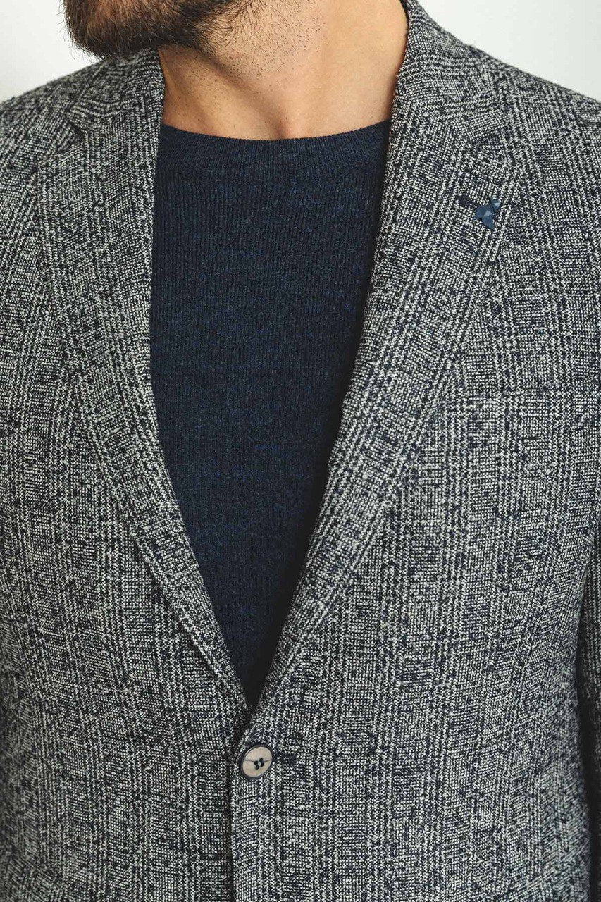 Man wearing a Charcoal Tweed Blazer with a pointed collar, flap pockets, and a slim fit, perfect for business meetings and formal gatherings.