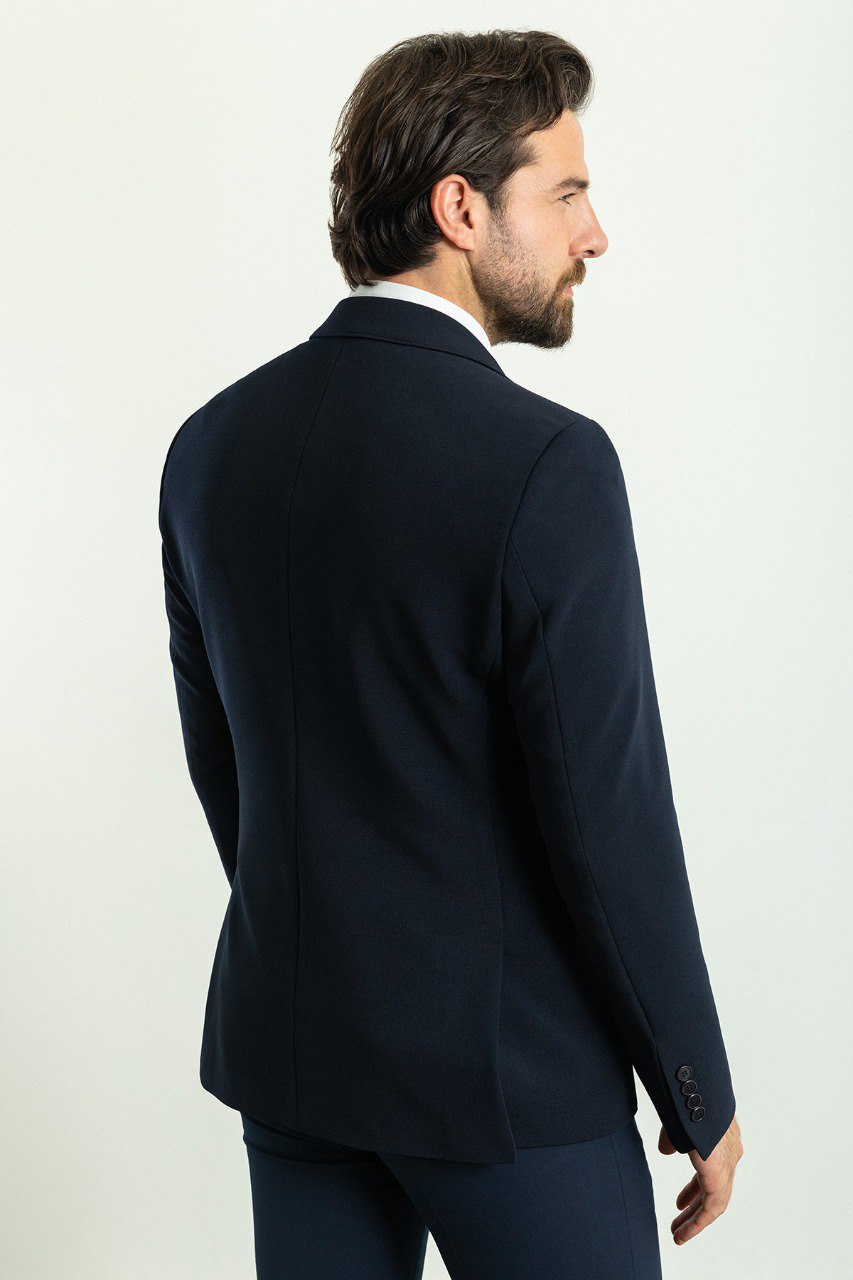 Man wearing a Nautical Nightfall Blazer with a sharp pointed collar, flap pockets, and a double-button closure, perfect for weddings and formal occasions.