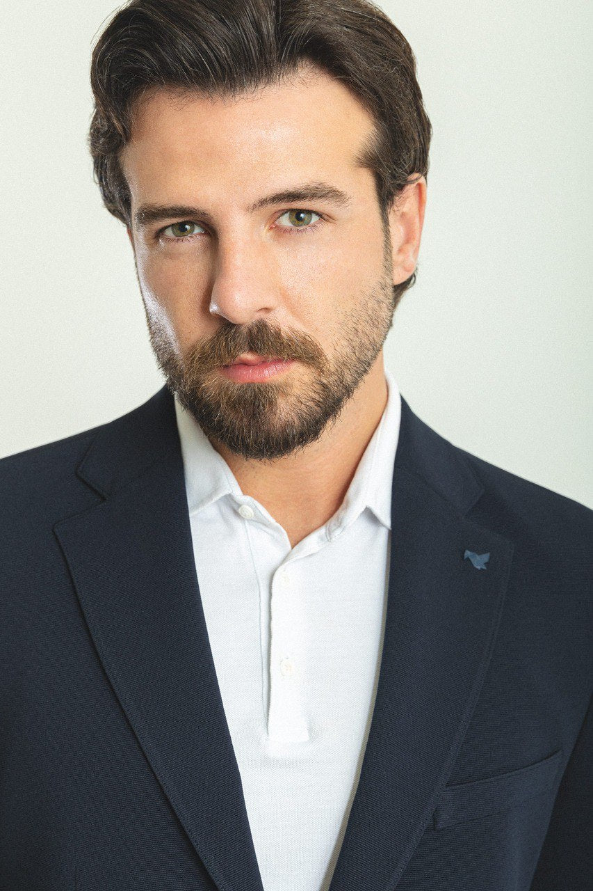 Man wearing a Nautical Nightfall Blazer with a sharp pointed collar, flap pockets, and a double-button closure, perfect for weddings and formal occasions.